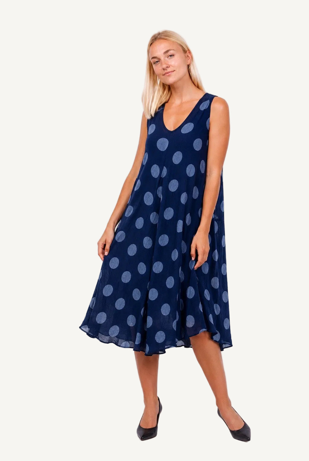 Woman wearing a navy dress with light blue polka dots on a white background