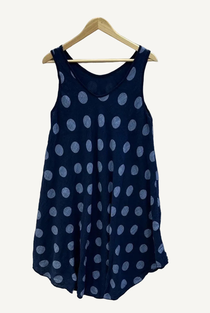 Navy blue sleeveless dress with white polka dots on a hanger against a white background