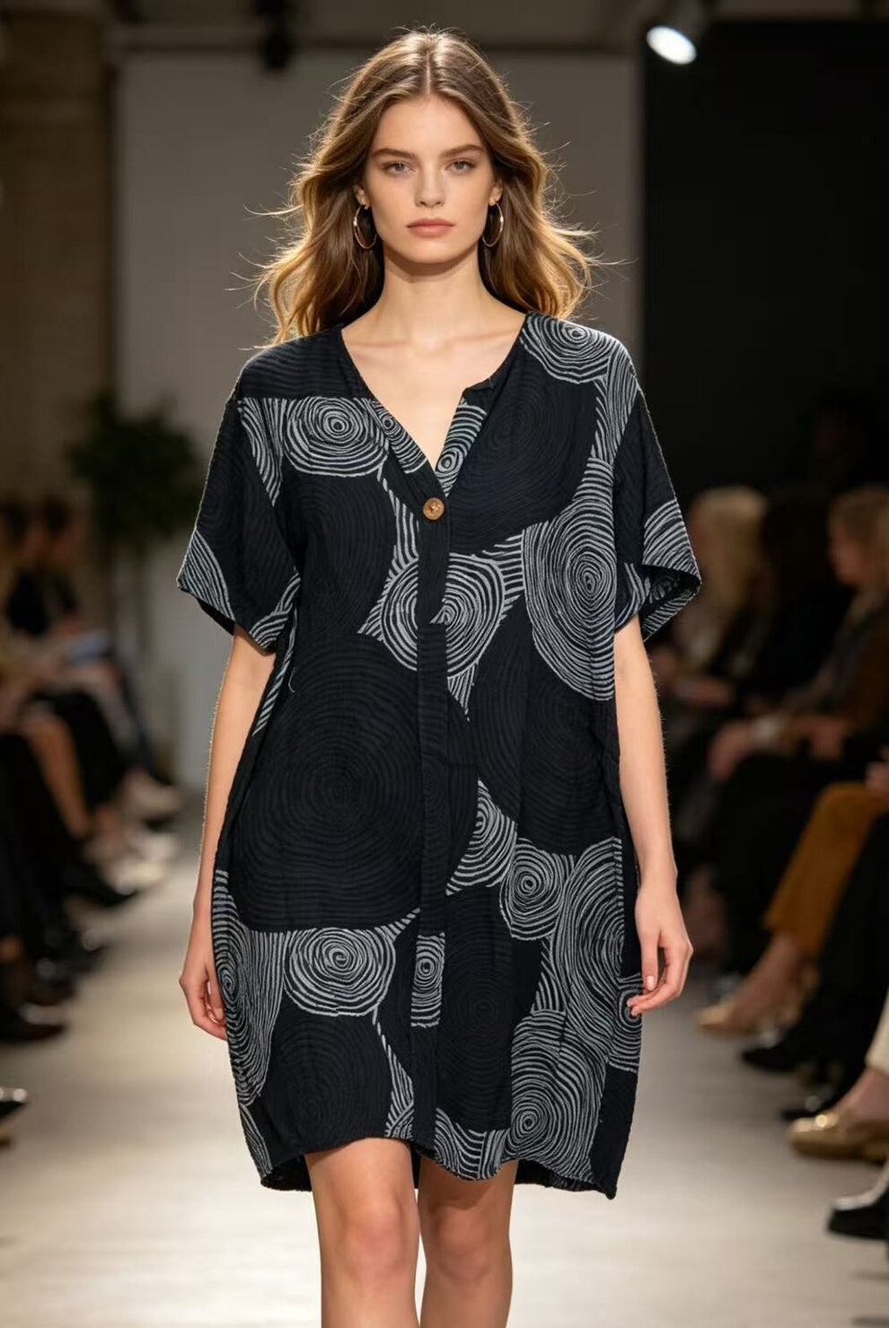 Model wearing a black dress with white patterns on a runway