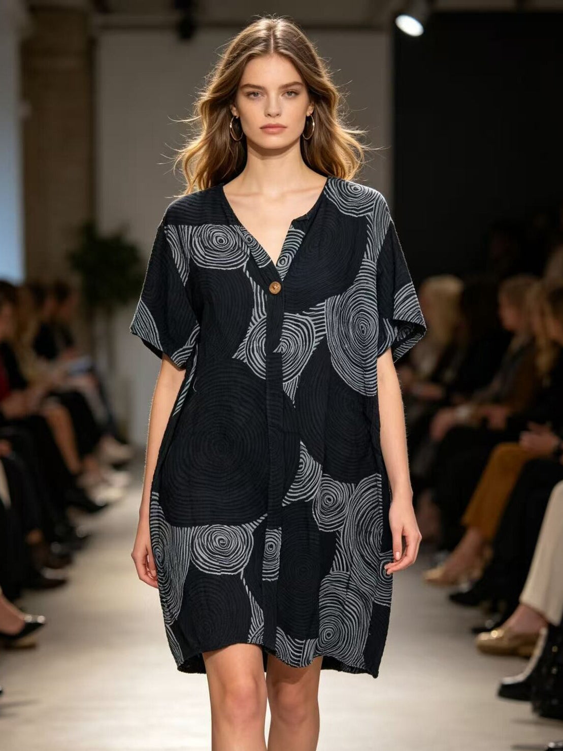 Model wearing a black dress with white patterns on a runway