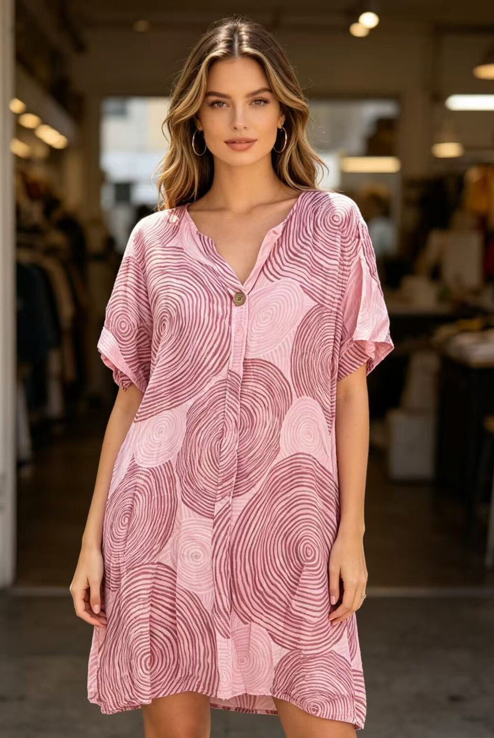 Woman wearing a pink patterned dress in an indoor setting