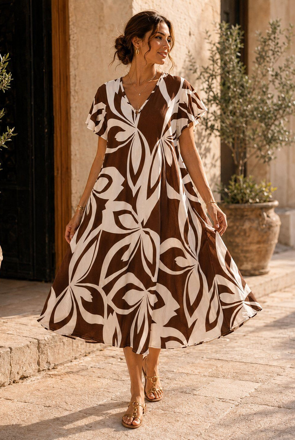 Woman wearing a brown and white patterned dress standing outdoors.
