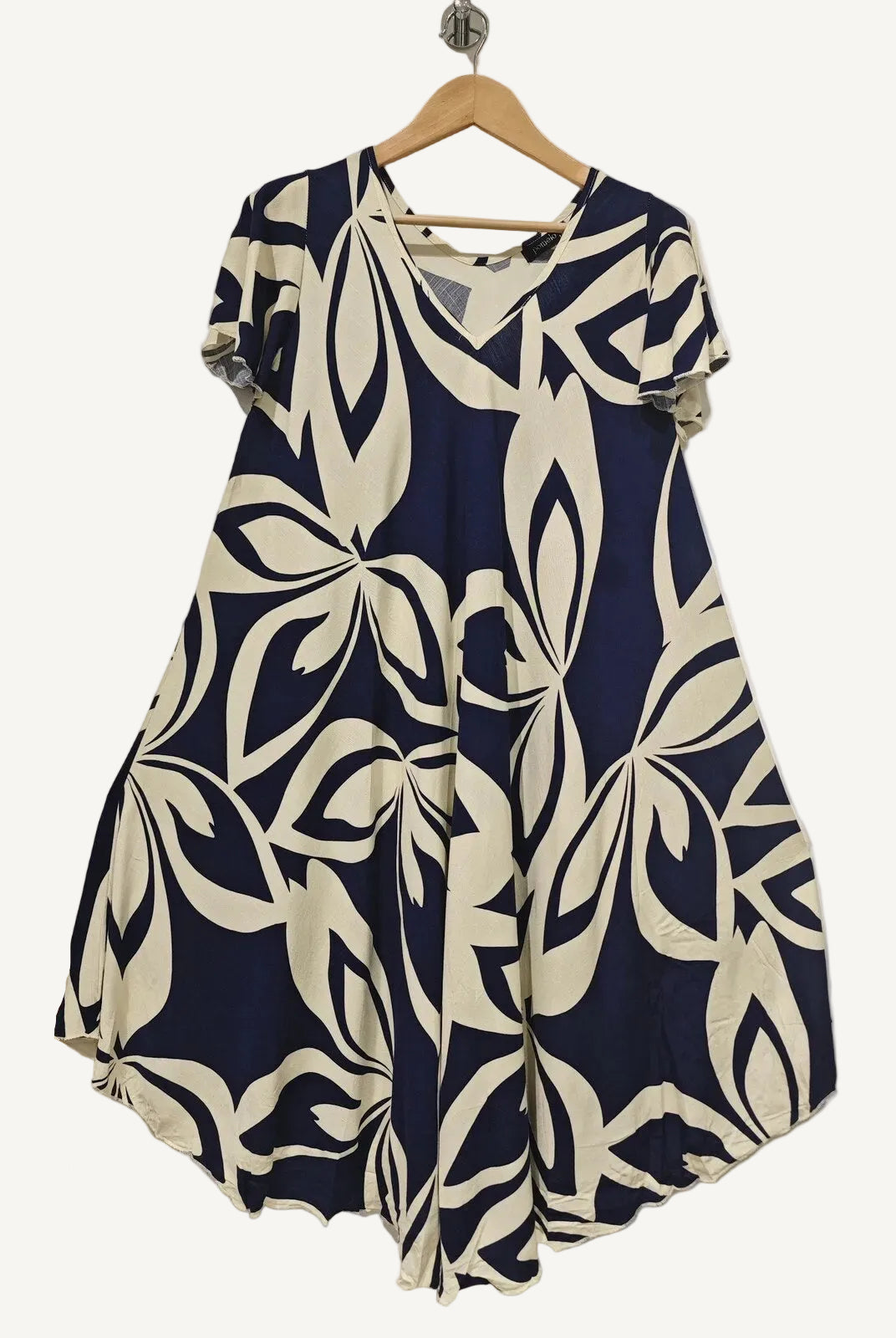 Navy and white patterned dress on a hanger against a plain background