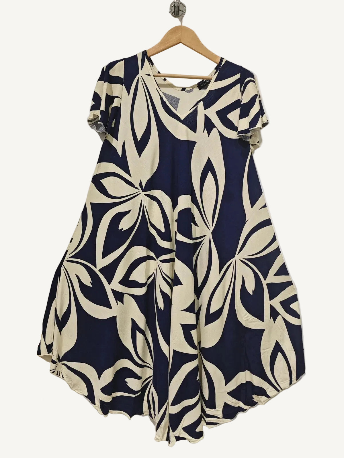 Navy and white patterned dress on a hanger against a plain background