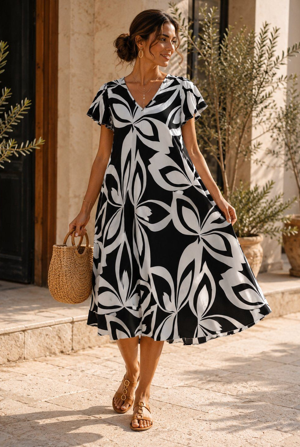 Woman wearing a black and white patterned dress standing outdoors.