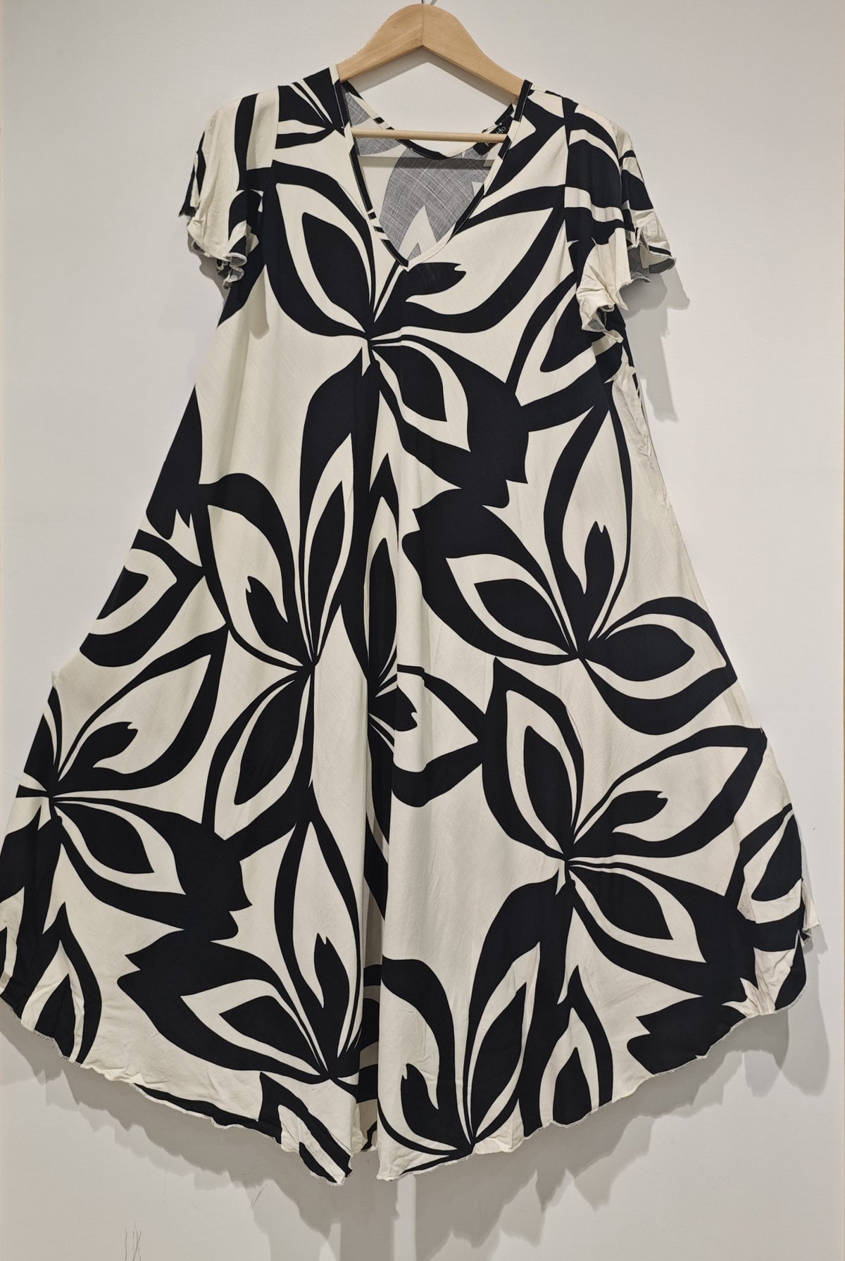 Black and white patterned dress on a hanger against a plain background