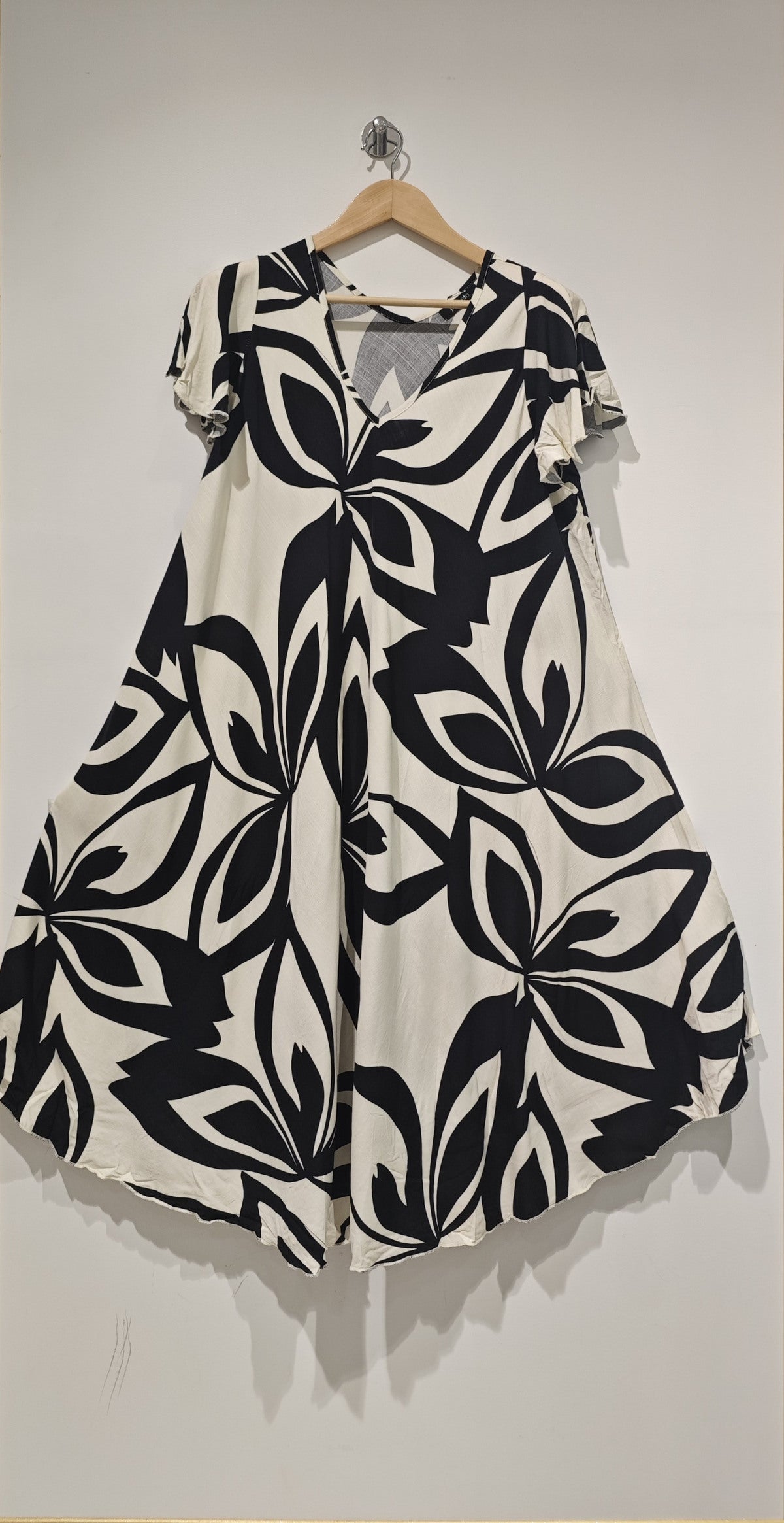 Black and white patterned dress on a hanger against a plain background