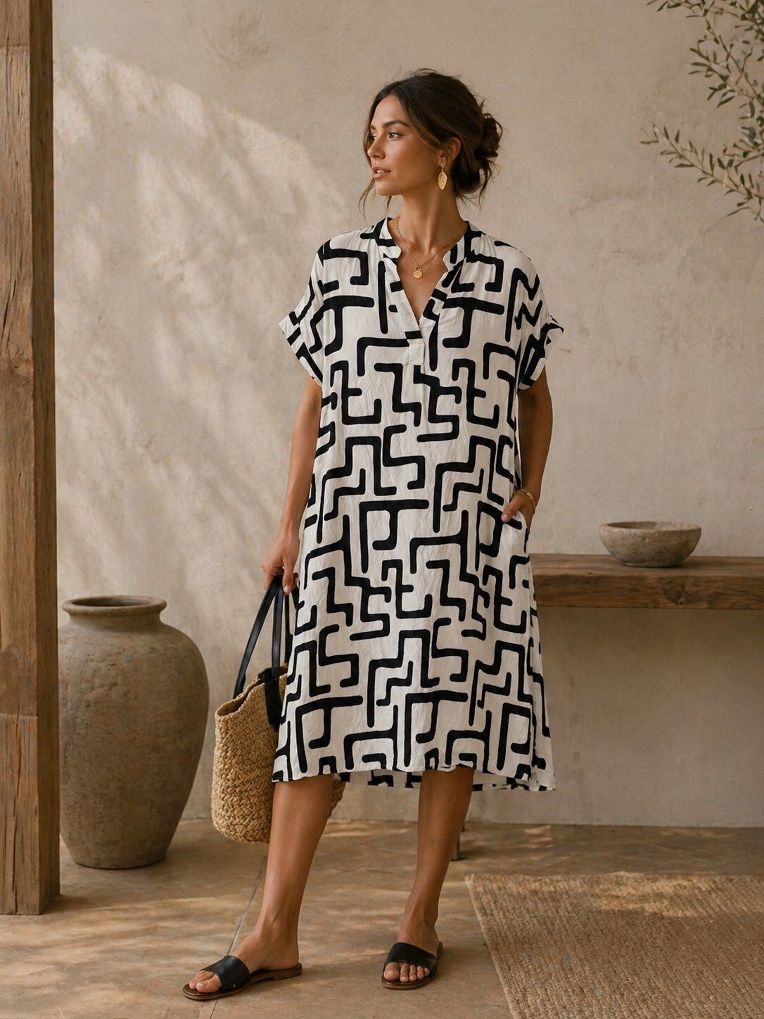Woman wearing a black and white patterned dress standing in a rustic indoor setting.