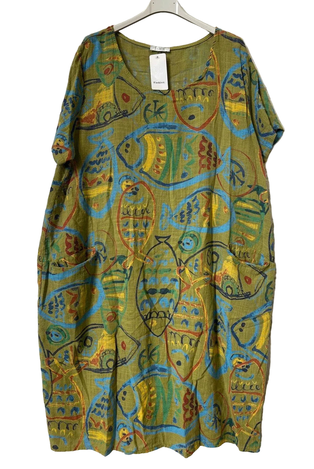 A short-sleeve tunic dress with an abstract fish pattern in olive green, yellow, blue, and red, hanging on a hanger against a textured gray background.