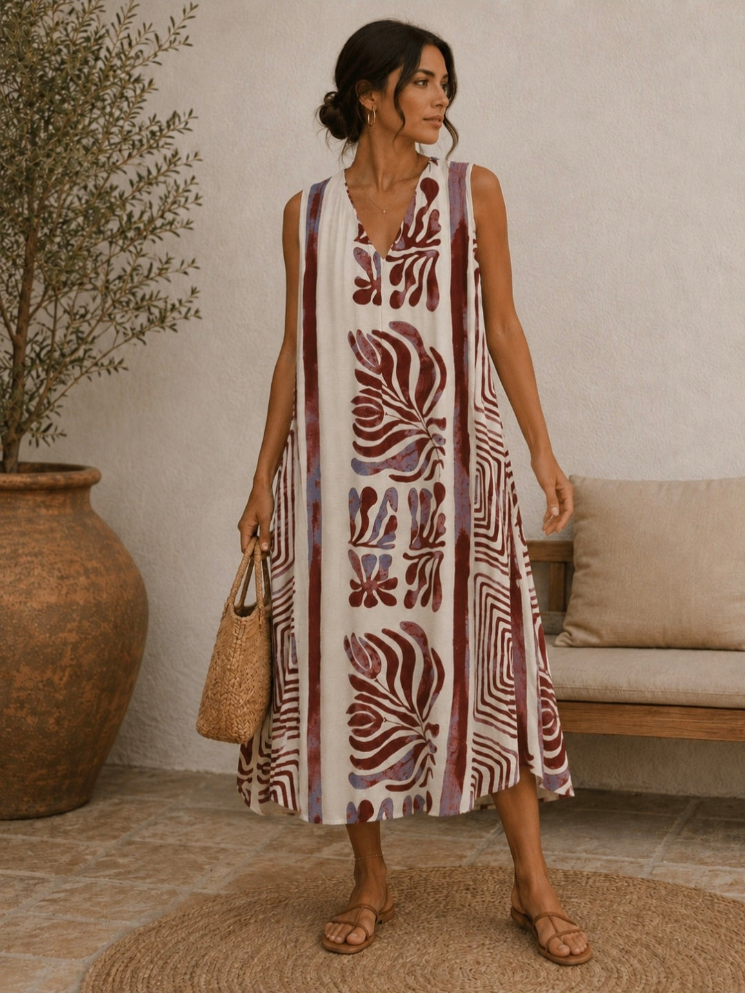 Woman wearing a patterned dress standing in a room with a vase and sofa.