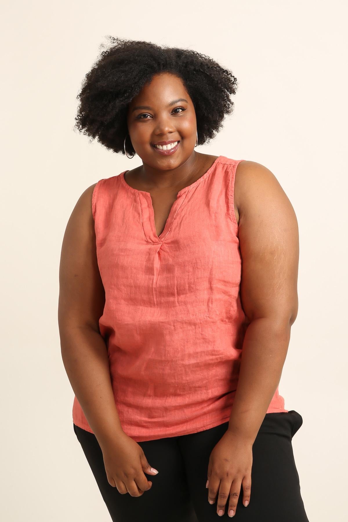 Woman wearing a coral sleeveless top against a beige background