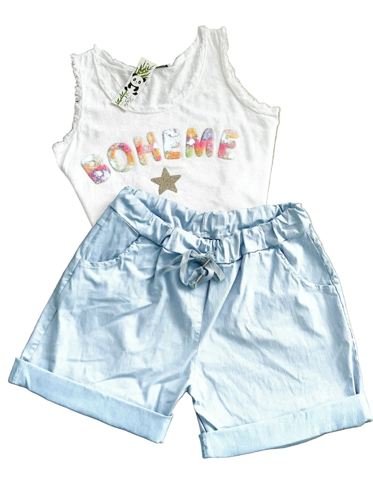 White sleeveless top with colorful text and light blue shorts on a wooden floor