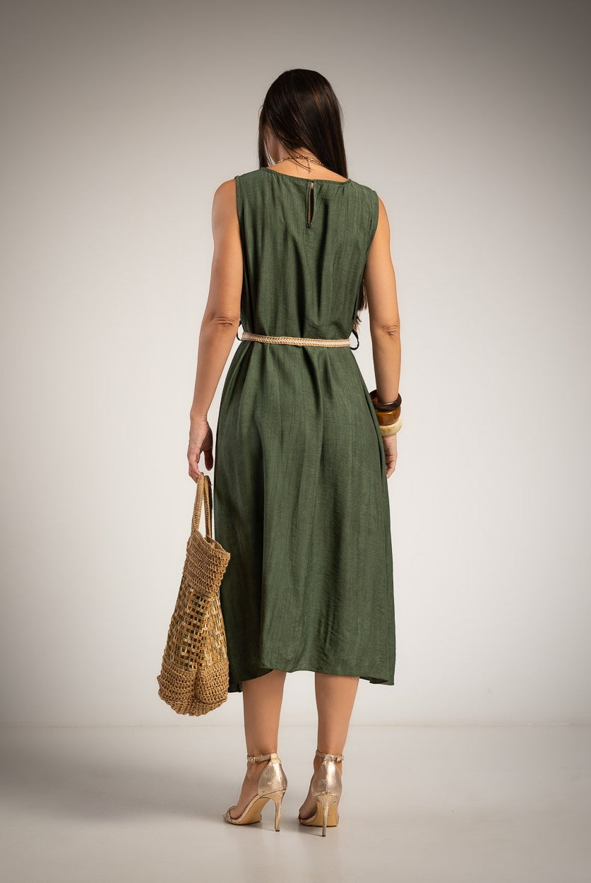 A woman stands with her back to the camera wearing a sleeveless olive green midi dress with a thin beige belt