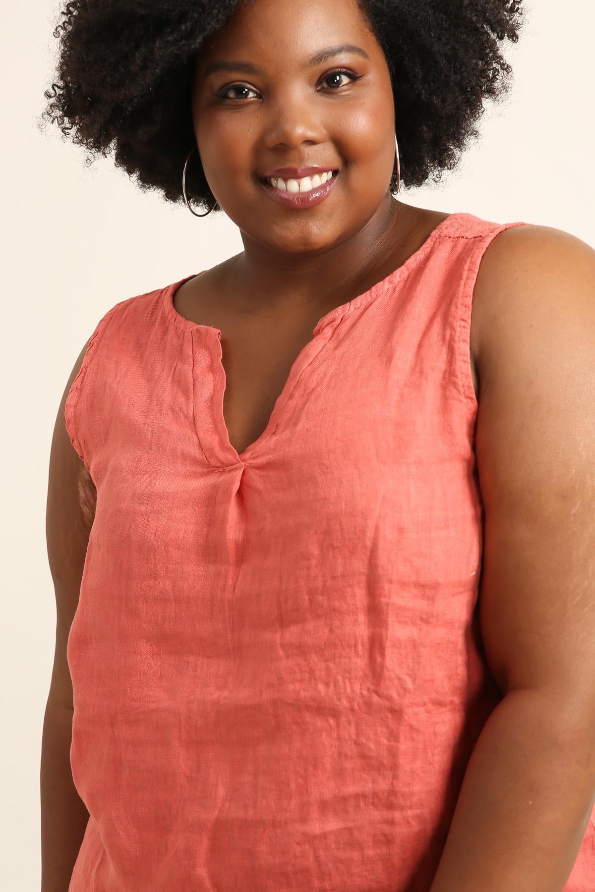 Woman wearing a coral sleeveless top against a beige background
