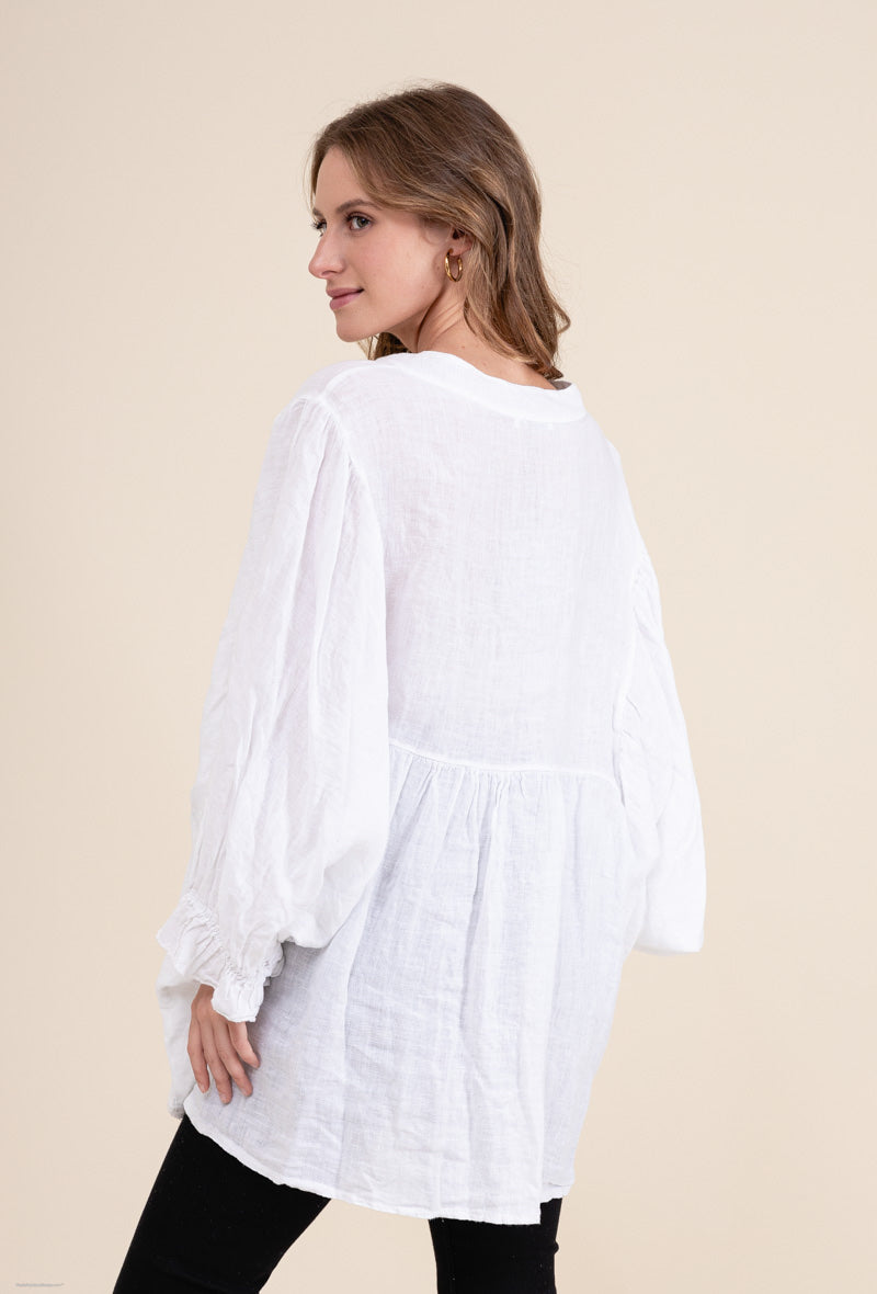 Woman wearing a white blouse with long sleeves on a beige background