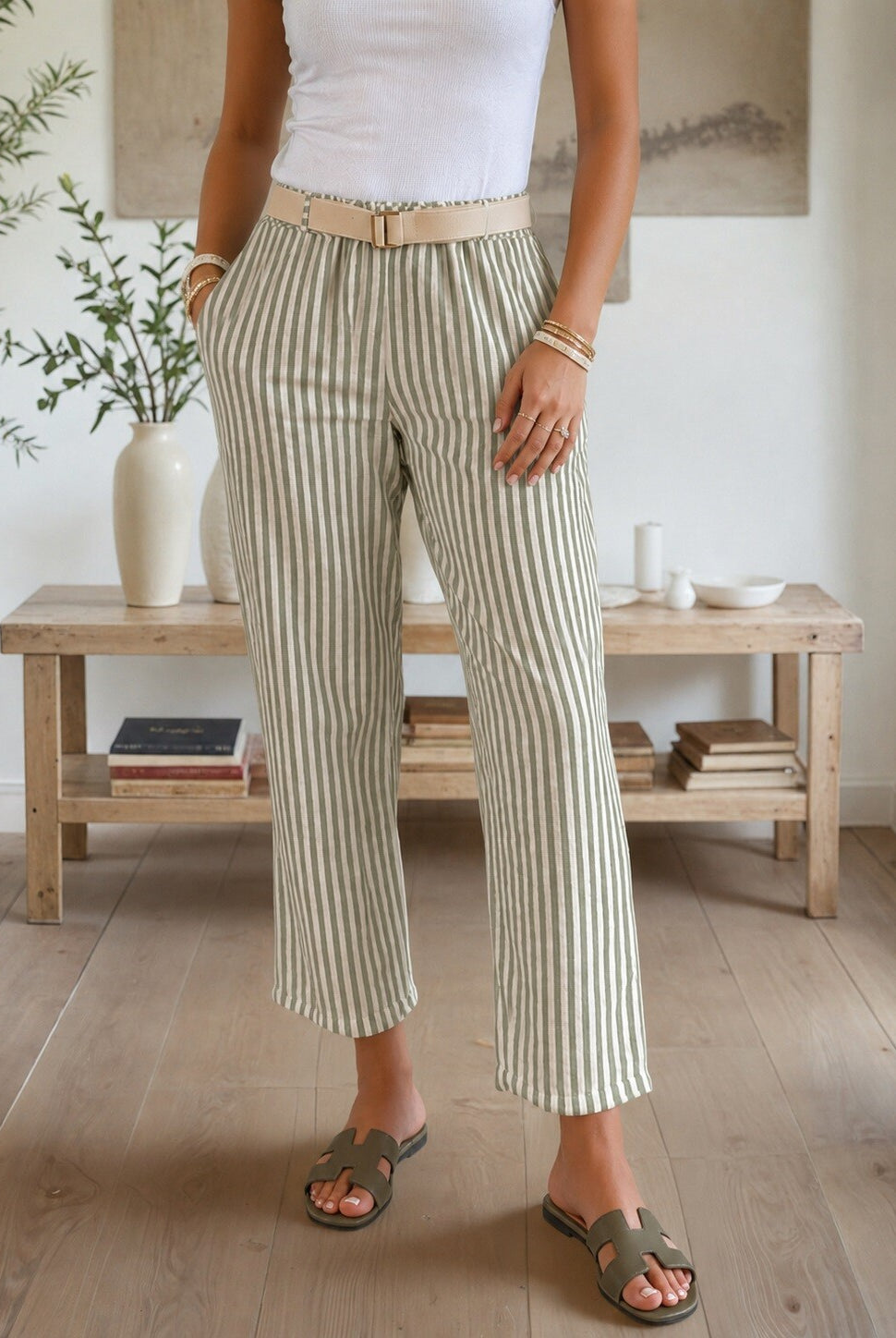 Person wearing striped pants in a room with wooden furniture and plants.