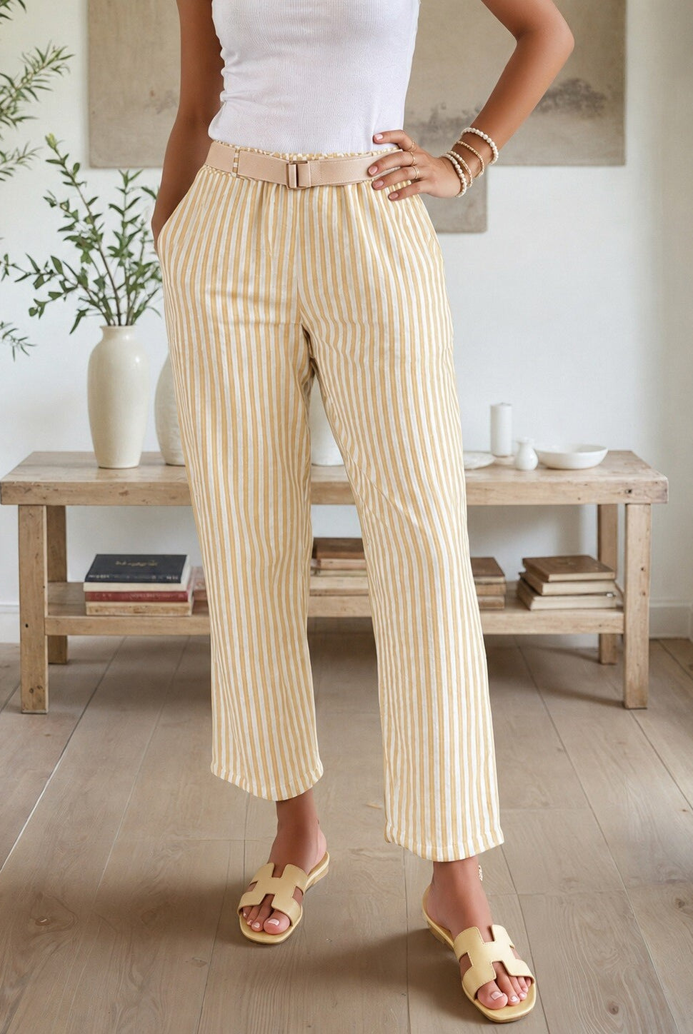 Person wearing striped pants in a room with wooden furniture and plants.