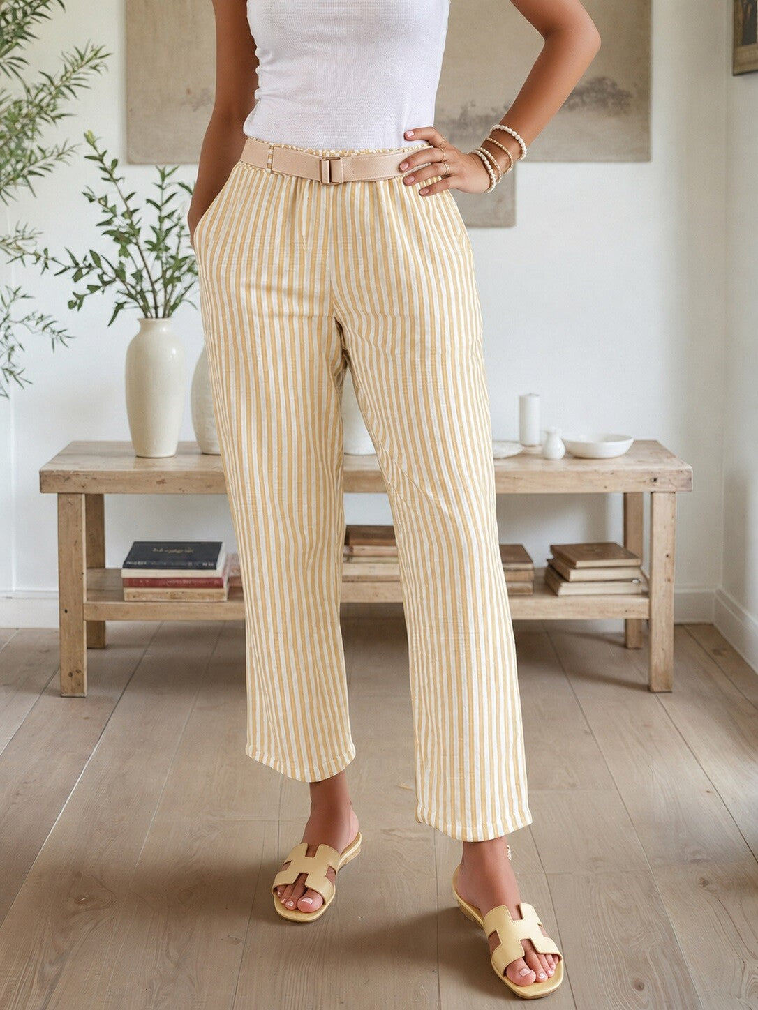 Person wearing striped pants in a room with wooden furniture and plants.