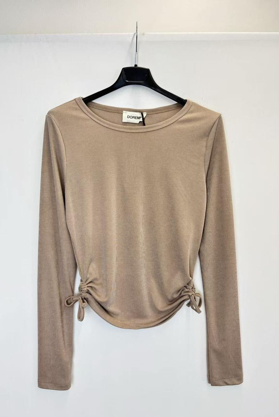 A beige long-sleeve knit top with side tie details