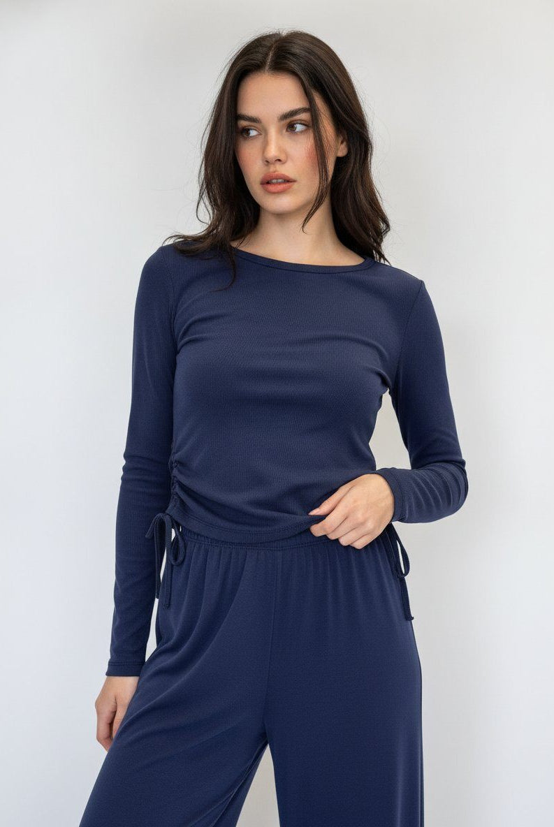 A woman modeling a navy blue long-sleeve ruched t shirt top with matching trousers