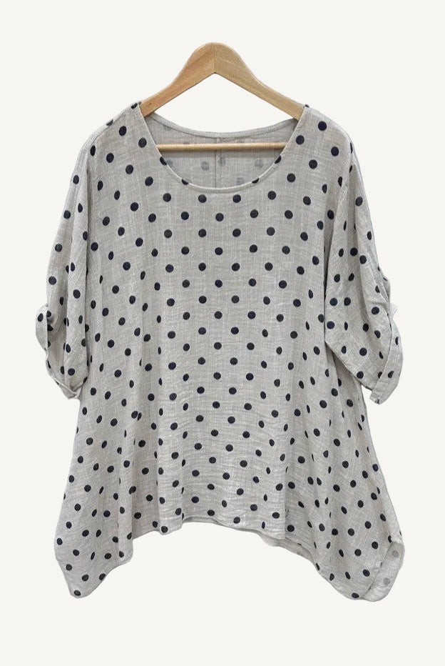 Beige sweater with black polka dots on a wooden hanger