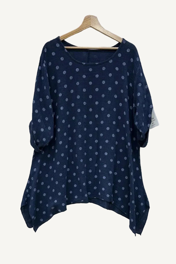 Navy blue blouse with white polka dots on a wooden hanger