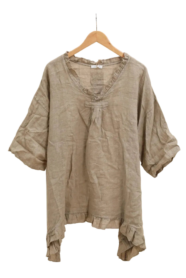 Taupe blouse with ruffled details on a hanger against a white background