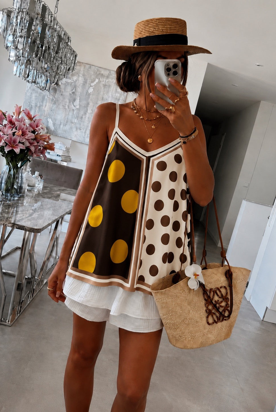 Person wearing a polka dot dress with a straw bag in a modern interior setting