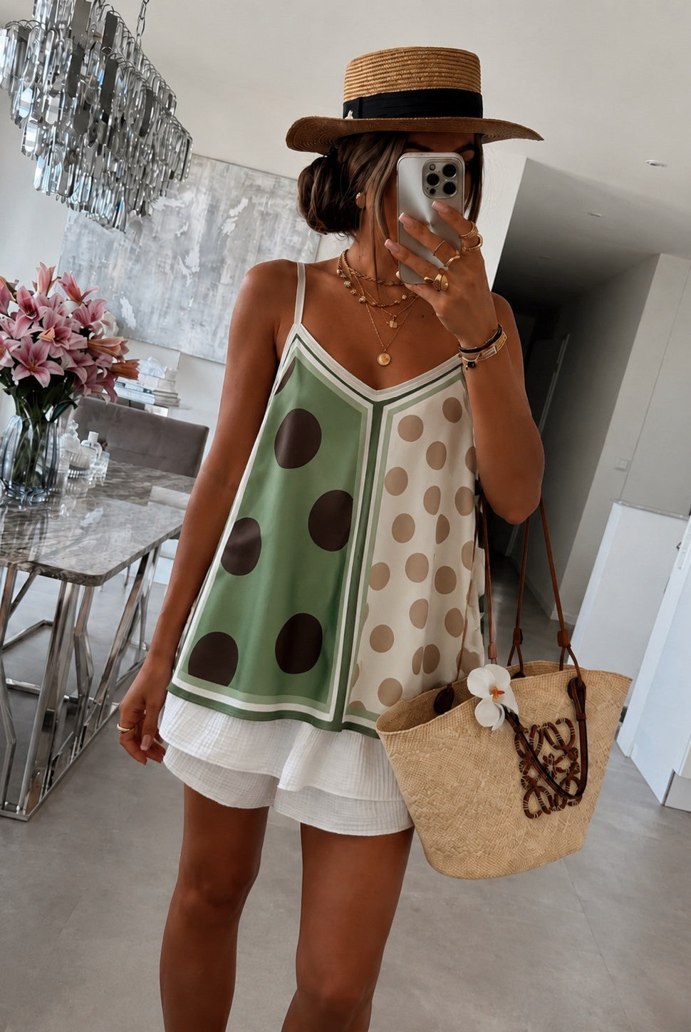 Person wearing a polka dot dress with a straw bag in a modern interior setting
