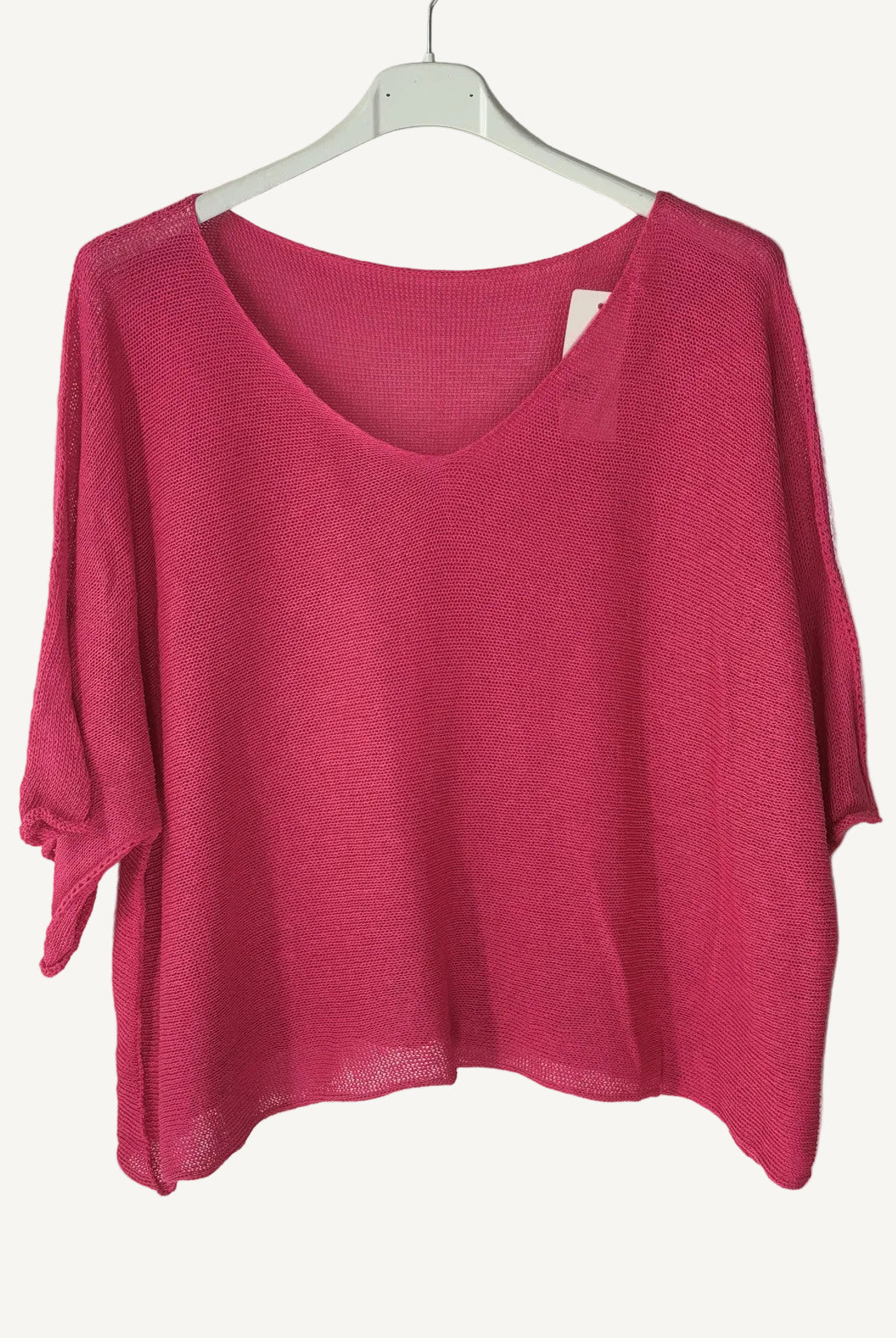 Pink sweater on a hanger against a light wall