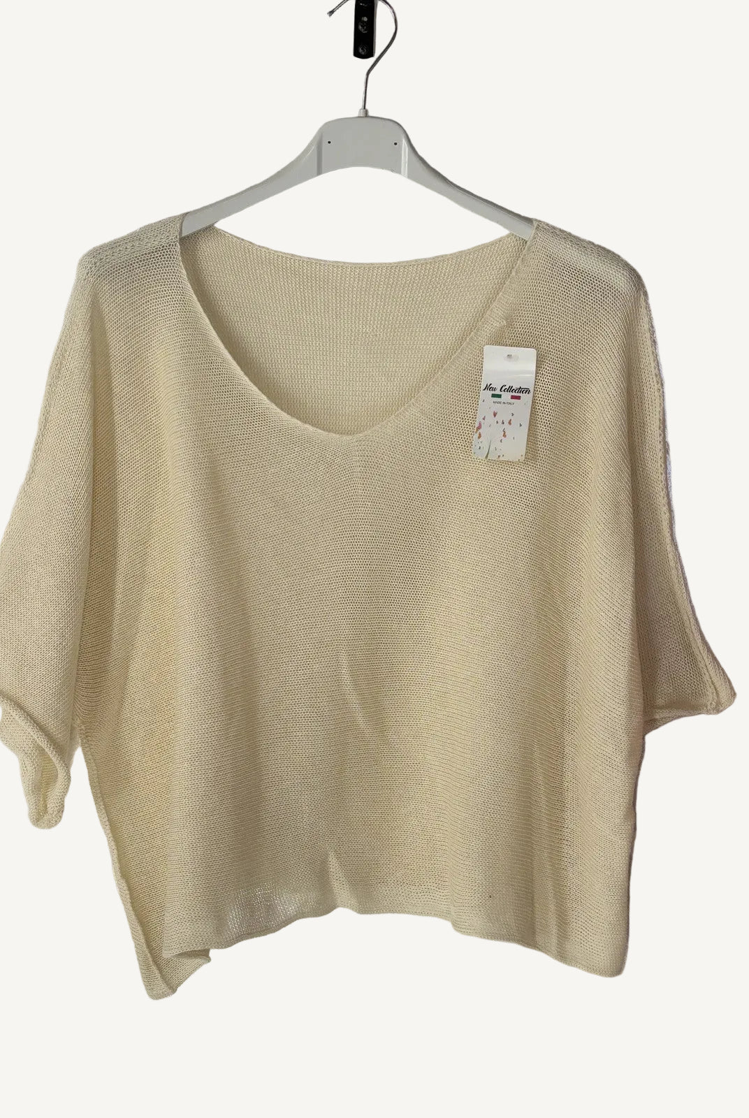 Beige sweater on a hanger against a beige wall