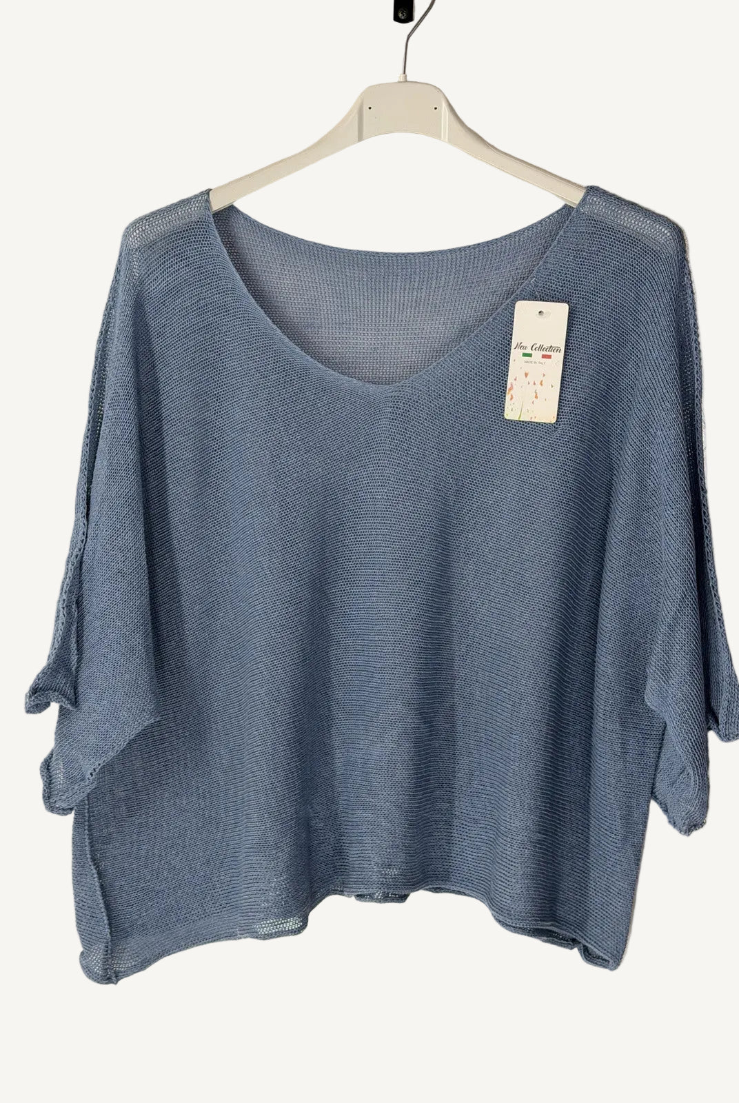 Blue sweater on a hanger with a beige background