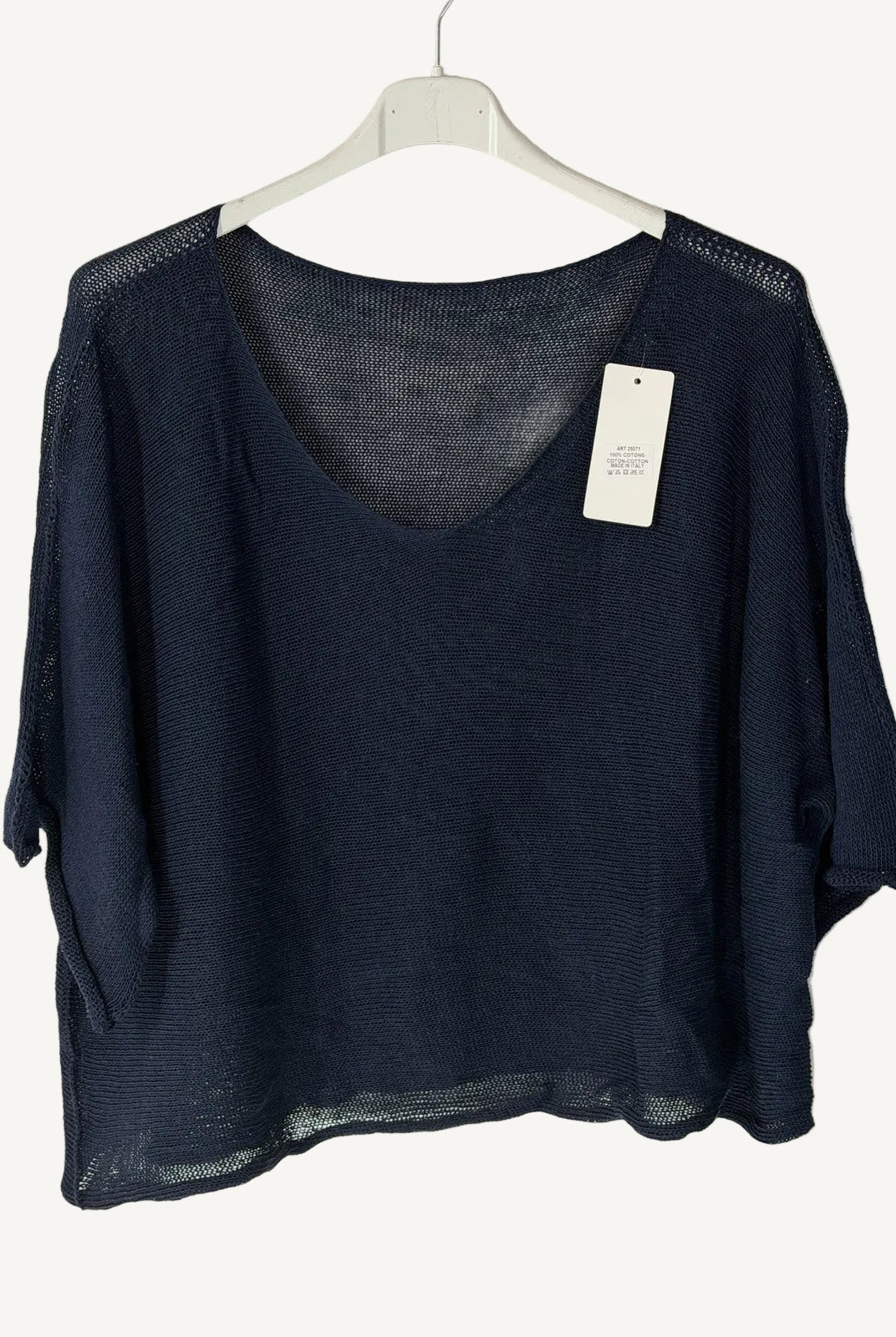 Black sweater with v neck on a hanger against a light background