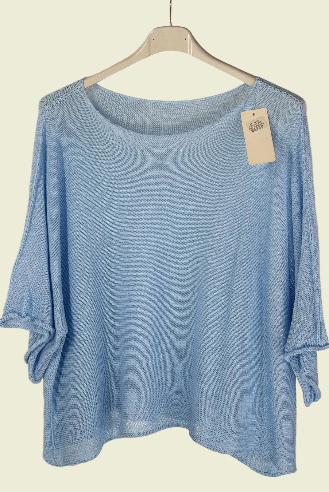 Blue sweater on a hanger with a tag against a neutral background