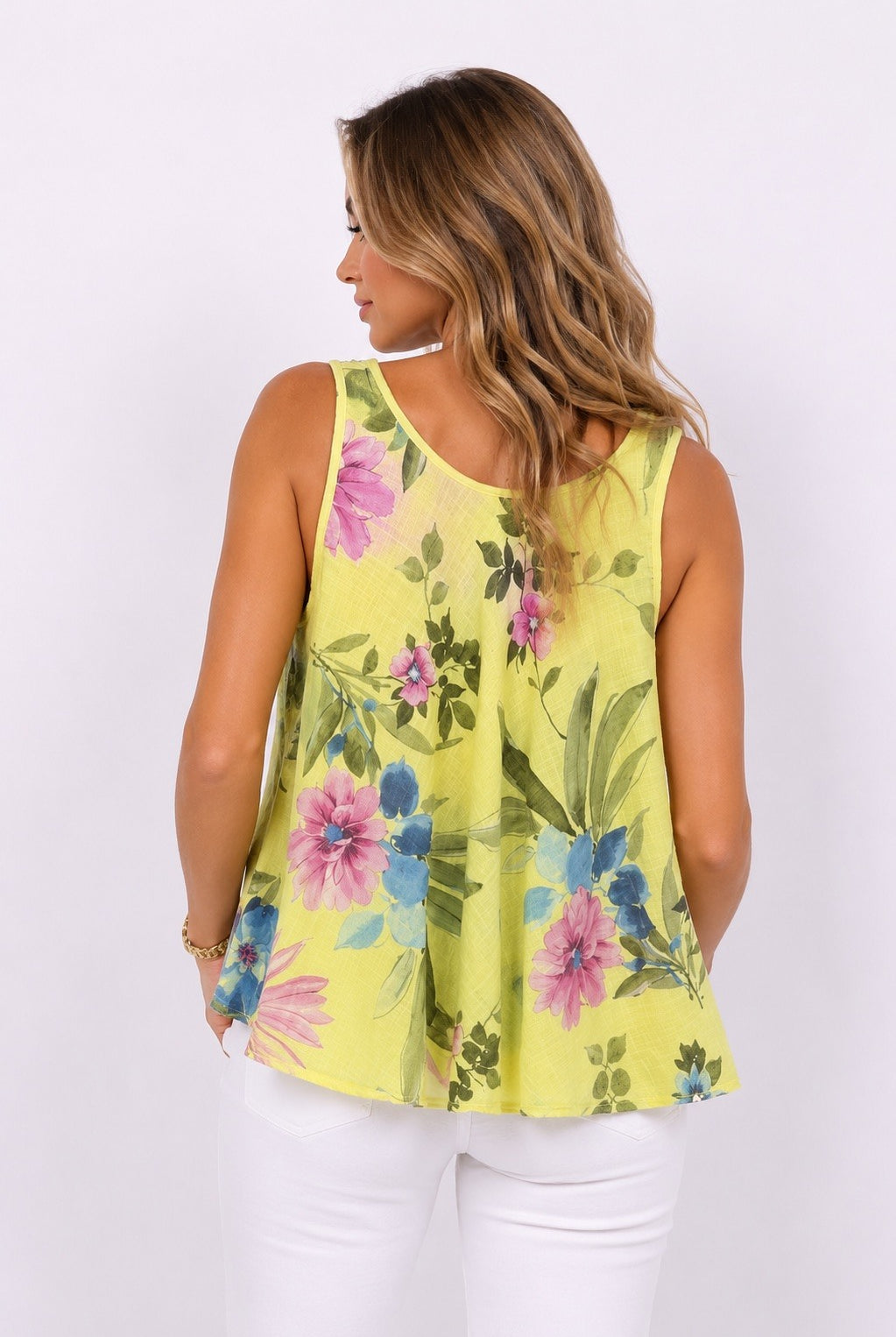 Woman wearing a yellow floral sleeveless top against a white background