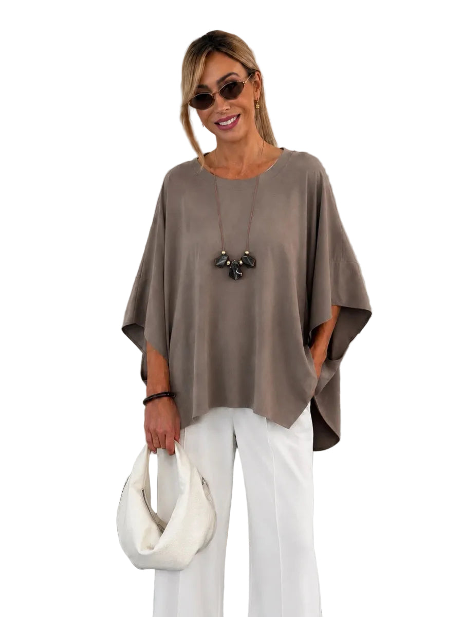 A woman wearing a taupe-brown short-sleeve bubble-neck top and white wide-leg pants