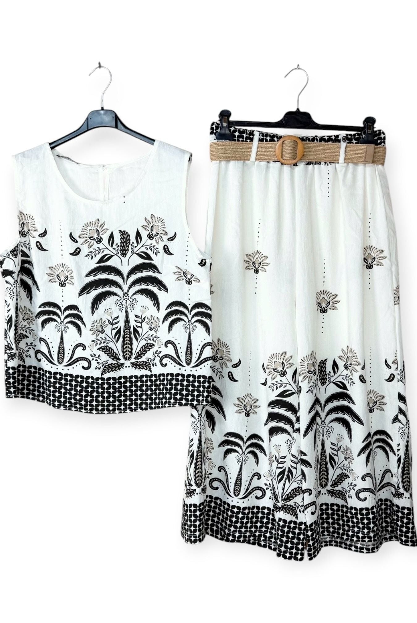 White top and skirt set with black floral patterns on hangers against a white background