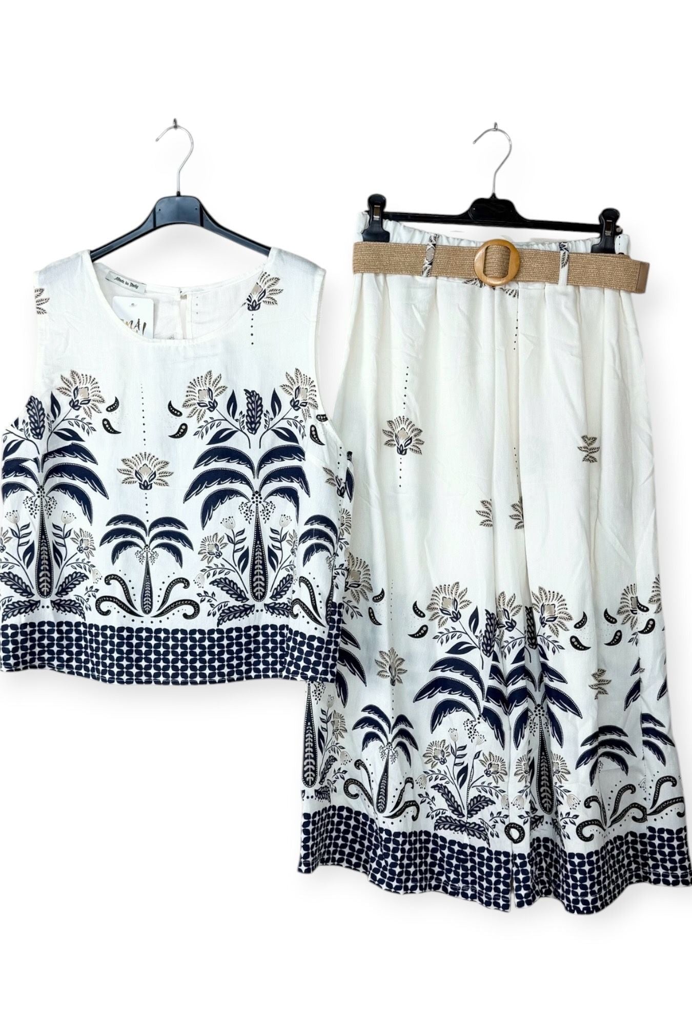 White outfit with navy floral patterns on hangers against a white background