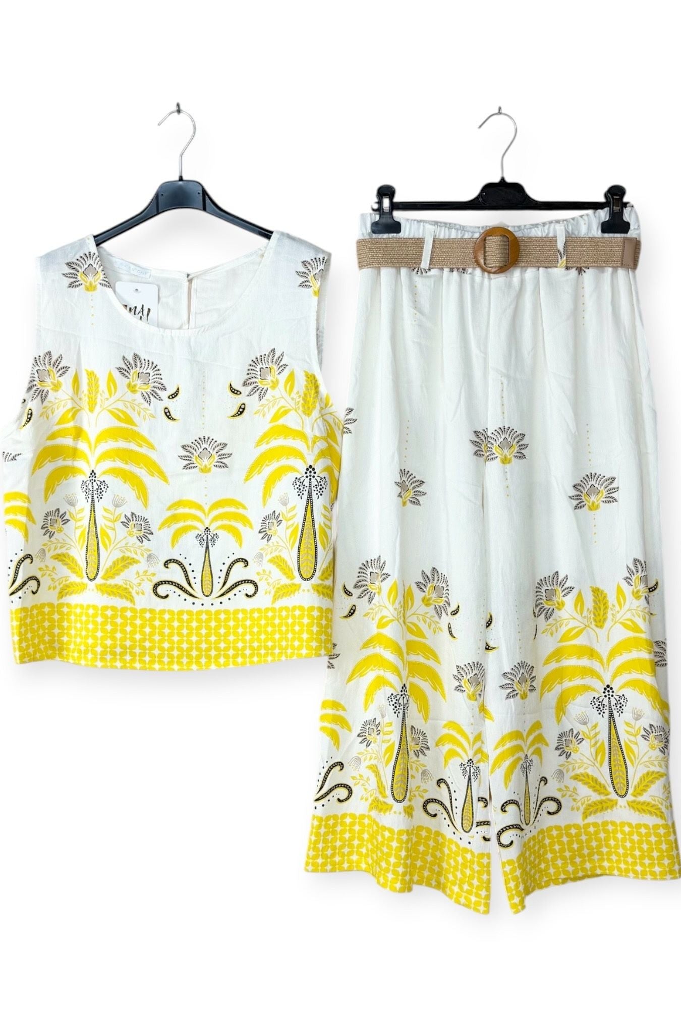 White outfit with yellow floral patterns on hangers against a white background