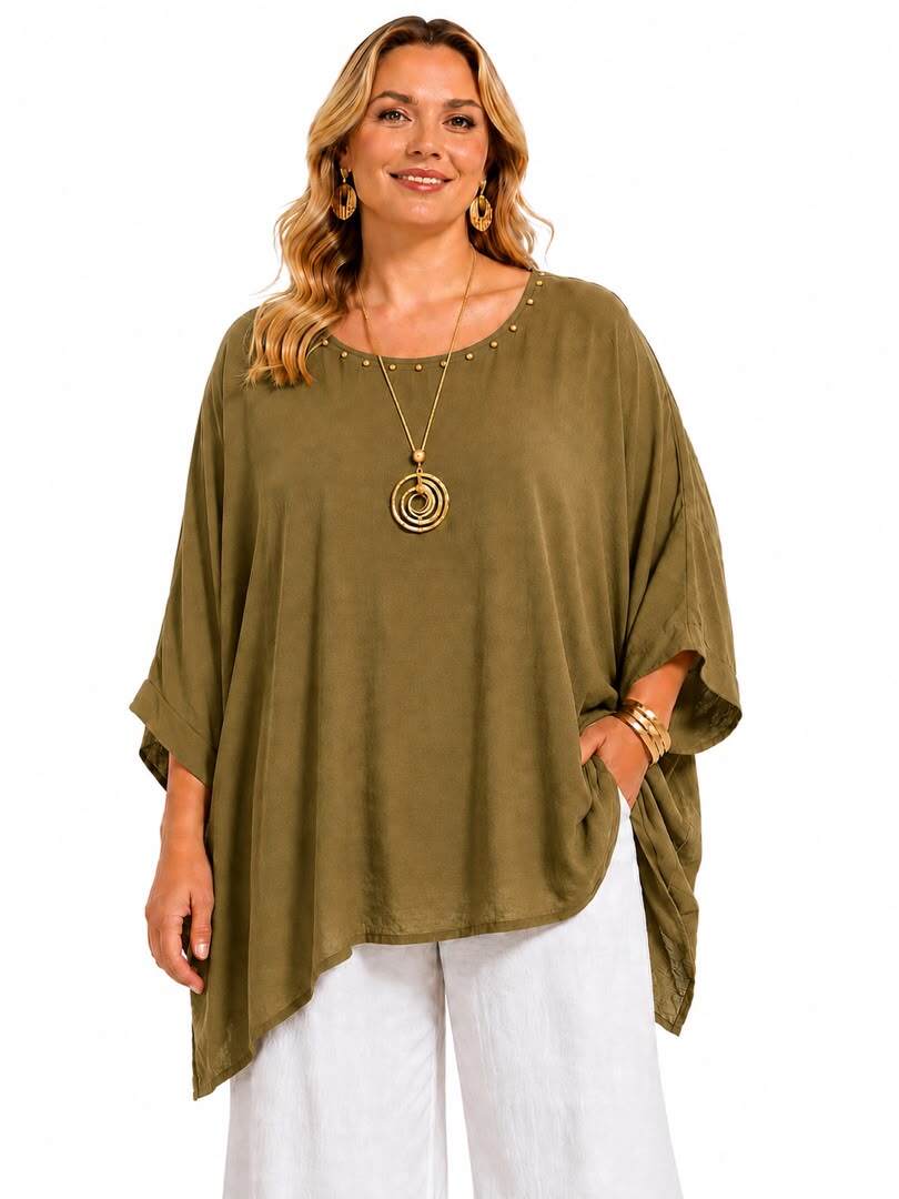 A woman modeling a loose, olive green short-sleeve top with a scoop neckline and small metallic studs, paired with white pants, against a plain white background.
