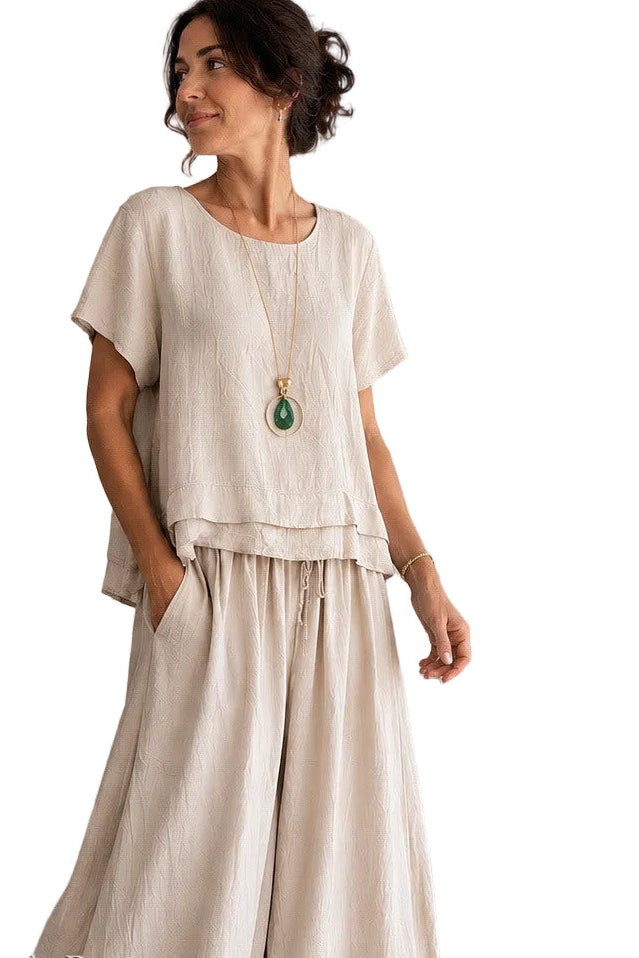 Woman wearing a beige outfit with a necklace on a white background