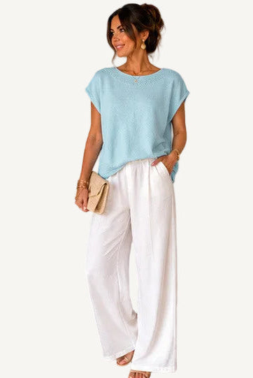 Woman wearing a light blue top and white pants, with product details displayed.
