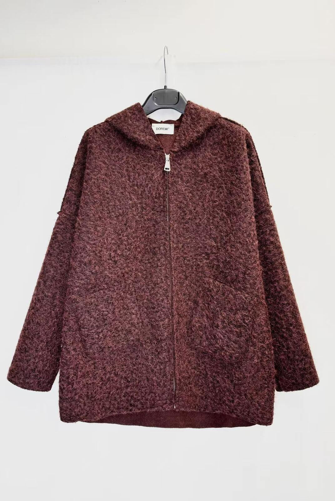 A textured, marled burgundy zip-up hoodie jacket hanging on a black hanger against a plain white wall.