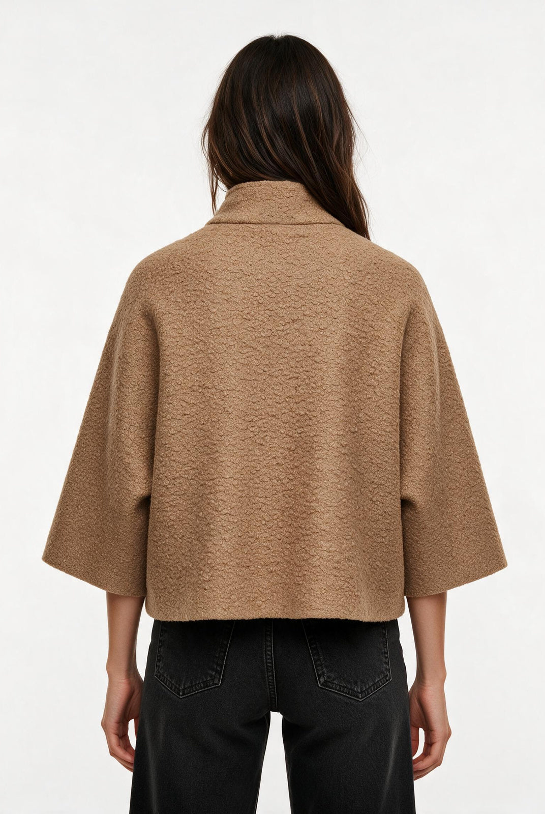 A model viewed from the back wearing a cropped, wide-sleeved camel-colored textured jacket and black jeans against a plain white background.
