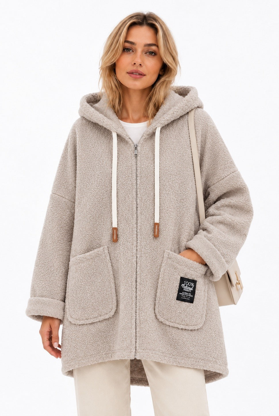 A woman wearing a light beige hooded zip-up coat with white drawstrings and large front patch pockets, photographed against a clean white studio background.