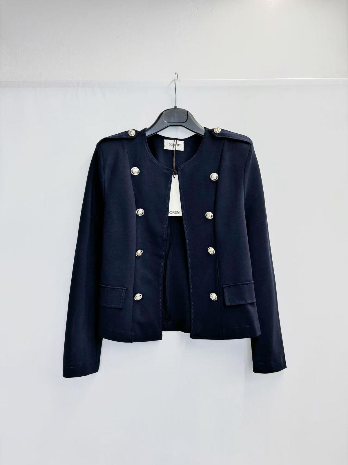 A dark navy blue cropped military-style jacket with silver-tone buttons, hanging on a black hanger against a plain white wall.