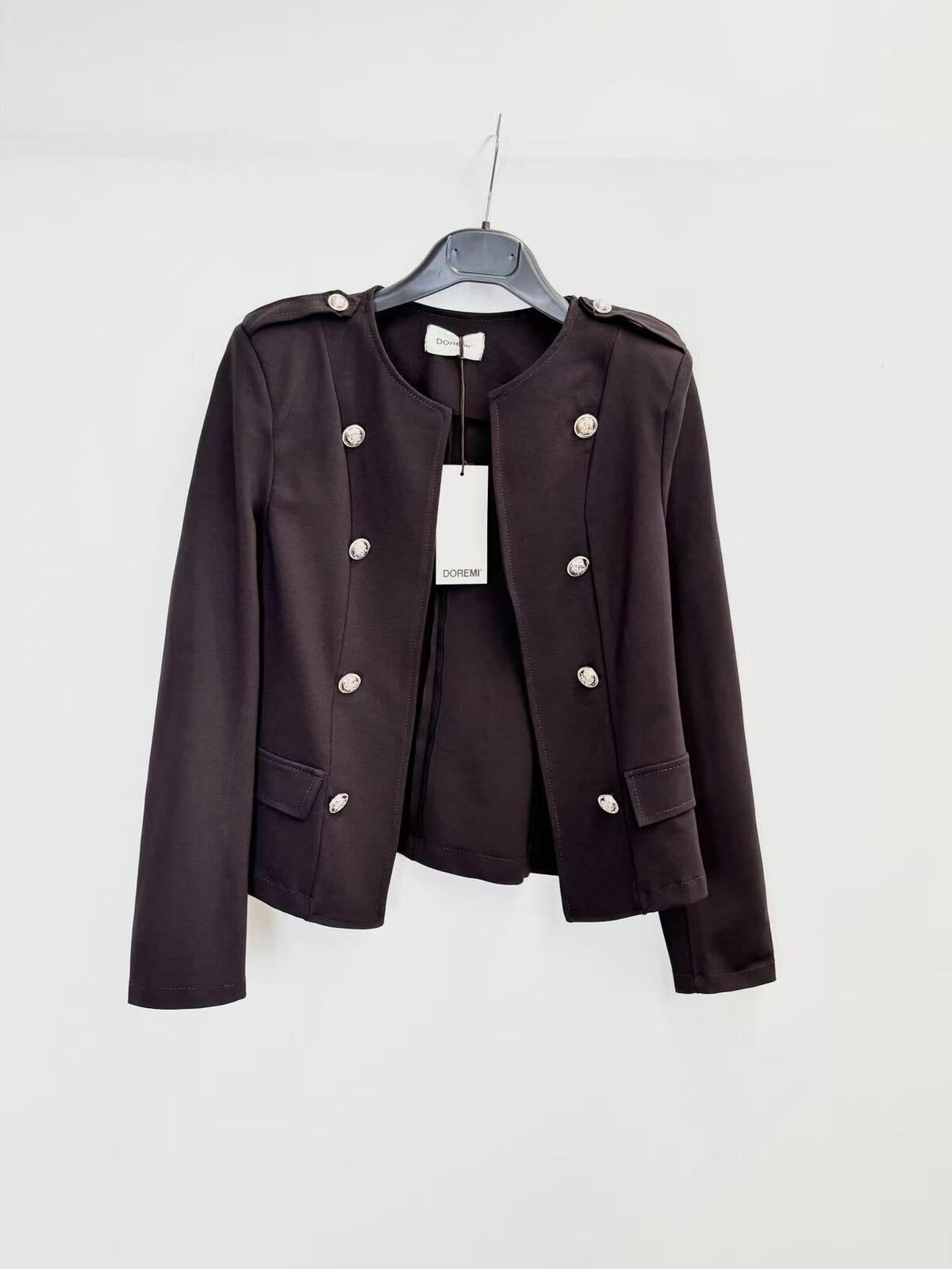 A dark brown cropped military-style jacket with silver buttons, hanging on a black hanger against a plain white wall.