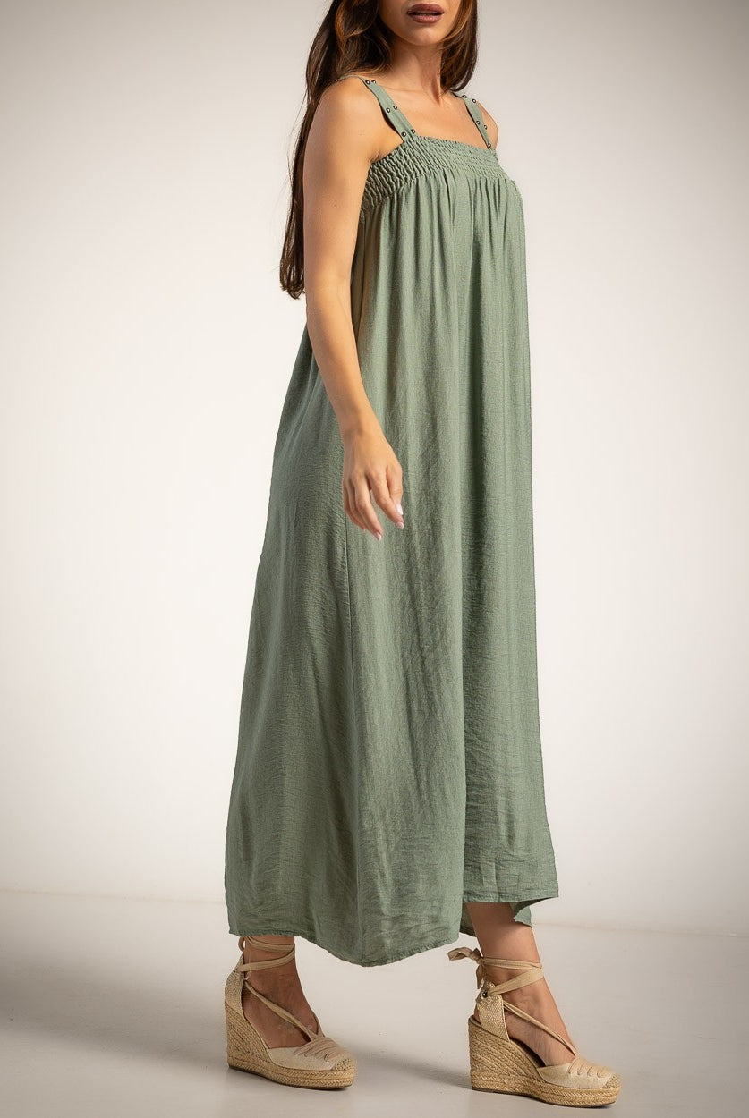 A woman modeling a green linen maxi dress with studded shoulder straps and a smocked bodice
