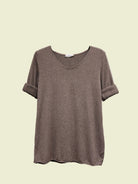 Brown t-shirt on a hanger against a neutral background