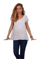 A person wearing a cream v-neck cap sleeve top with a loose fit.